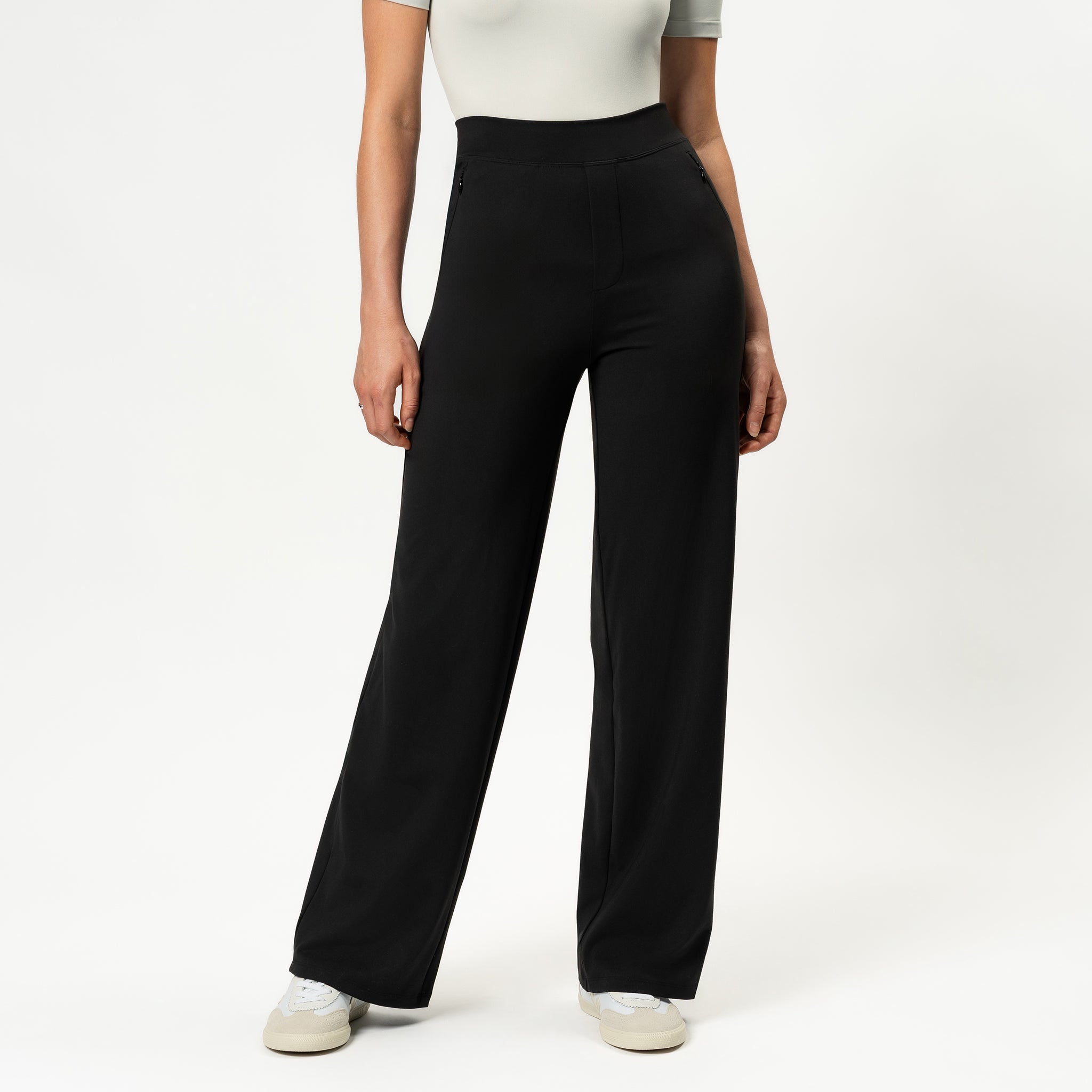 Front view of model wearing black Ninepine Asana Relaxed Straight Pants with a white T-shirt and sneakers.